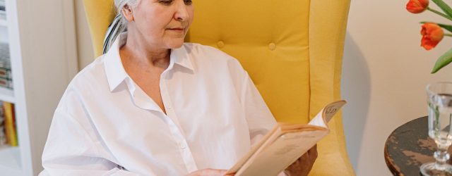 femme âgée en train de lire dans un fauteuil jaune