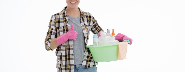 femme qui porte des gants de ménage et qui tient une bassine remplie de produits